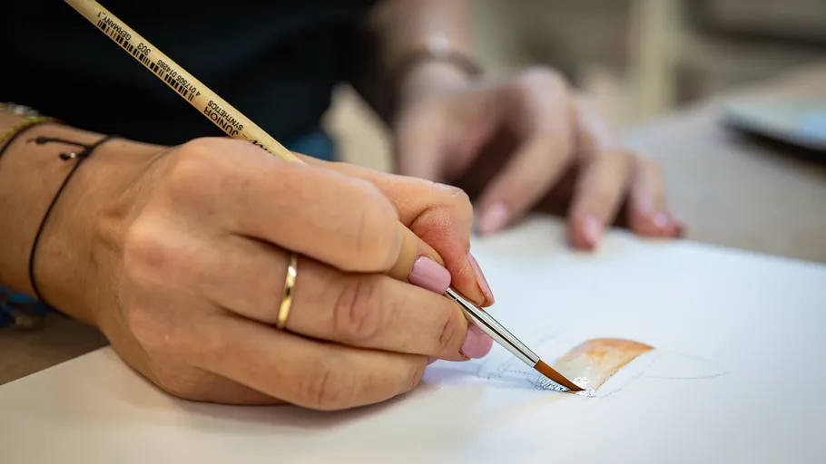 Hand painting paper with a brush indoors.
