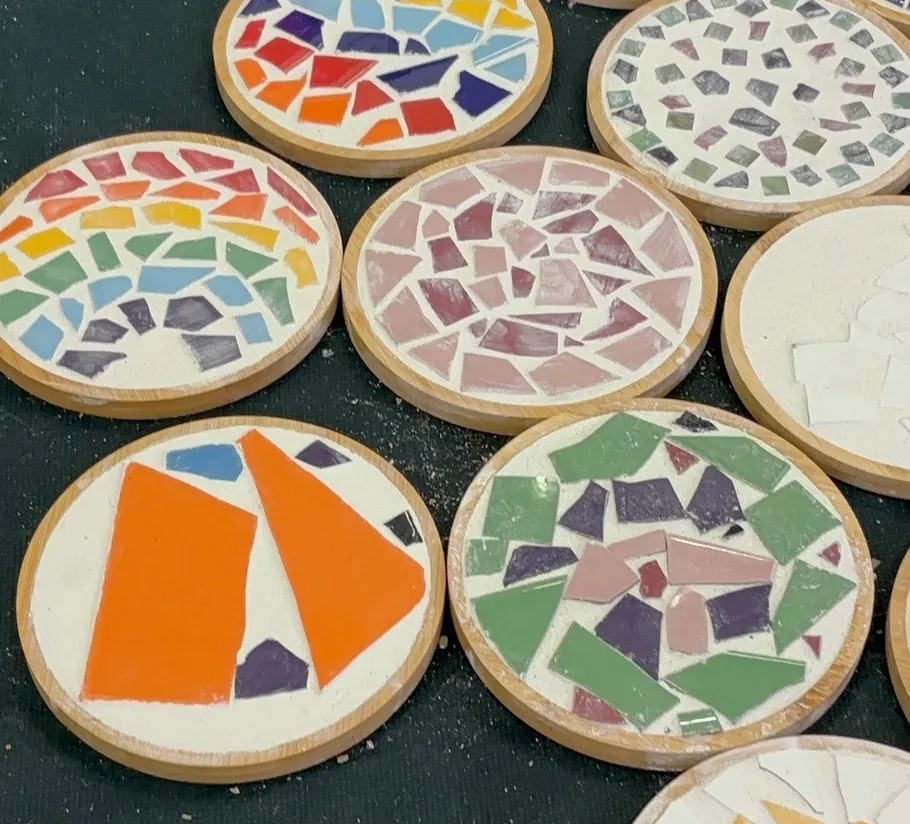 Colorful mosaic coasters on dark surface.