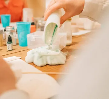 Person gießt Flüssigkeit in Form auf Tisch.