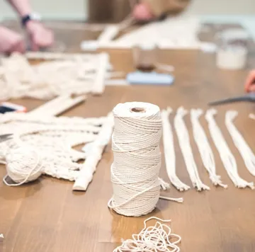 Twine spool and cords on a wooden table.
