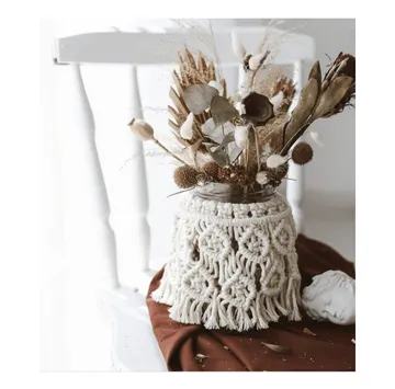 Macrame jar with dried flowers on chair.