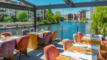 Tische in verglastem Restaurant am Fluss.