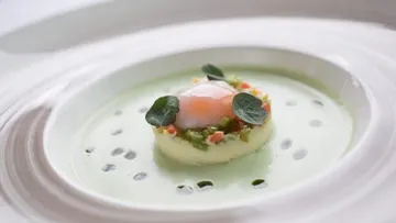 Gourmetgericht mit pochiertem Ei und Sauce.