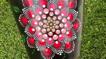 Bunte Punktkunstblume auf schwarzer Oberfläche.
