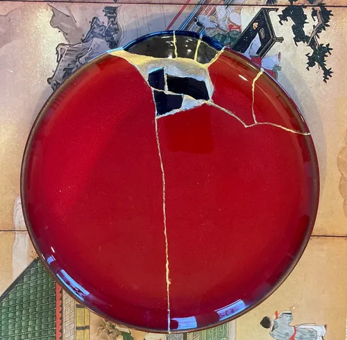Roter Teller mit Kintsugi auf Kunstwerk repariert.