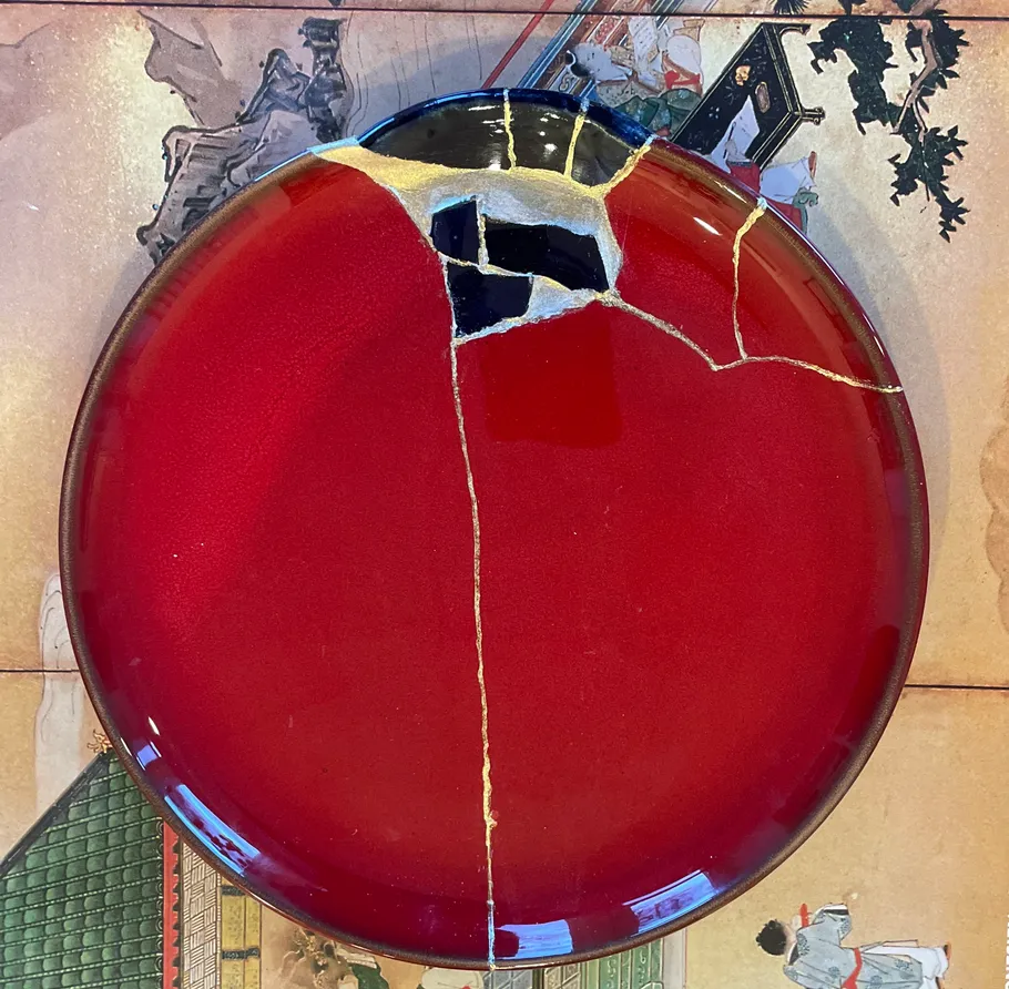 Red plate repaired with Kintsugi on artwork.