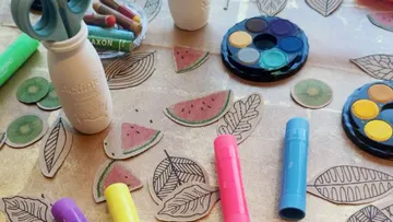 Bastelmaterialien auf Tisch mit Papiersymbolen.