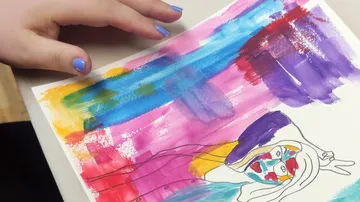Hand hält buntes abstraktes Gemälde auf Papier.
