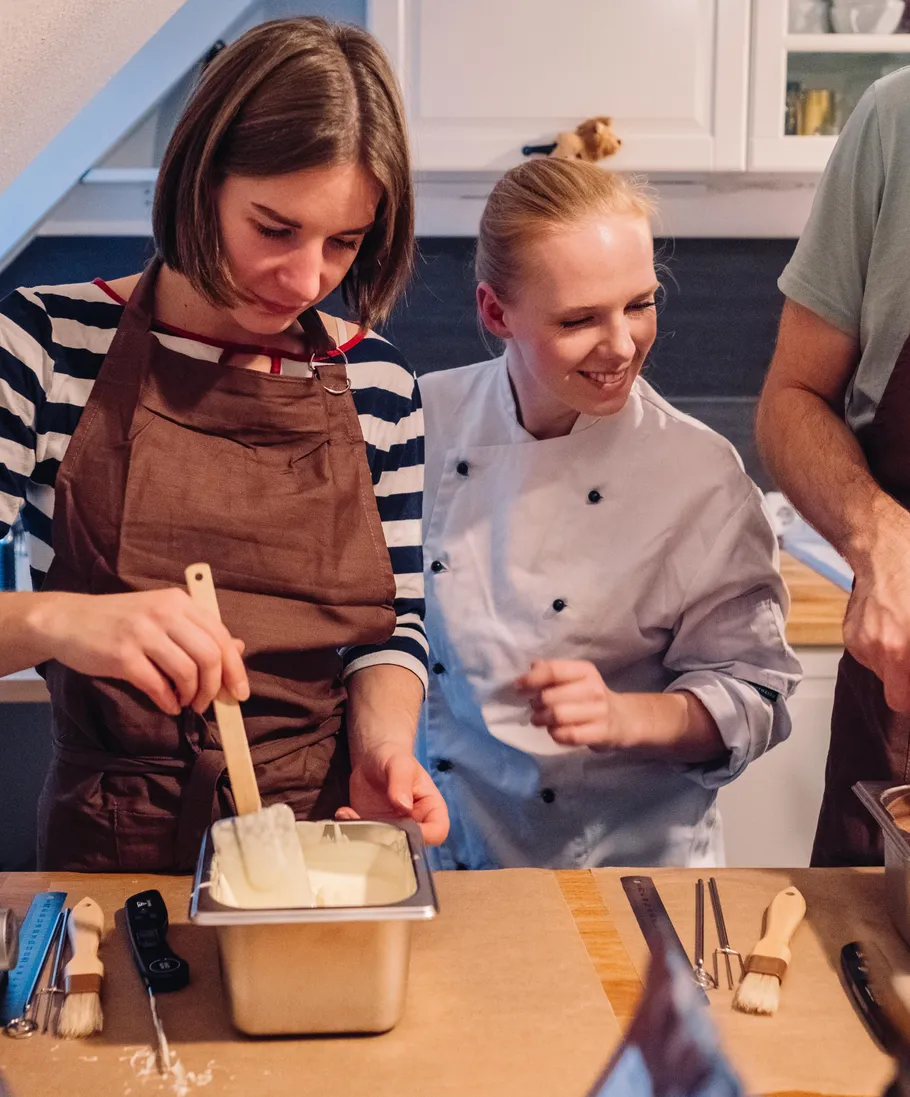 Two women stirring batter in kitchen setting.