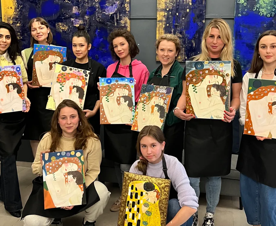 Group of women holding paintings in art class.