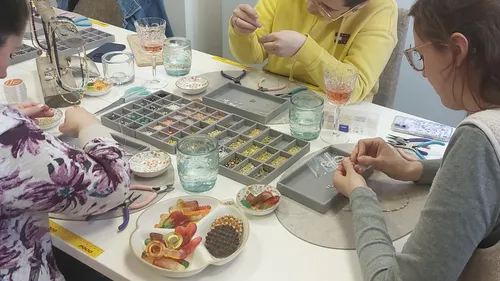 People making jewelry at a table workshop.