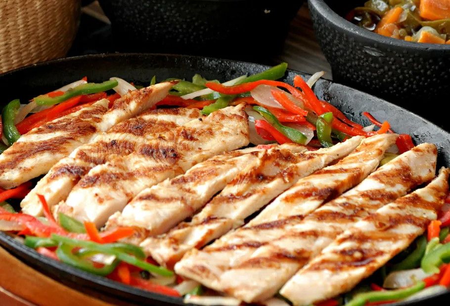 Grilled chicken with peppers on a skillet.