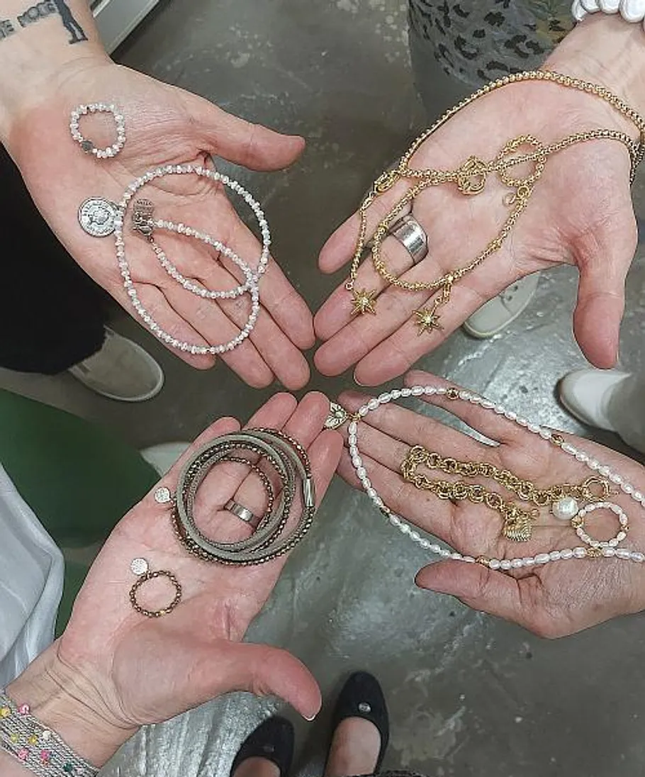 Hände halten Schmuck auf Betonboden.