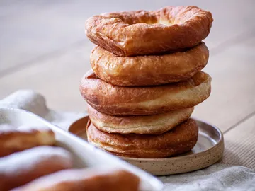 Stacked golden brown bagels on a plate are ready.