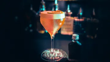 Cocktail mit Zitrusgarnitur auf Bartresen.