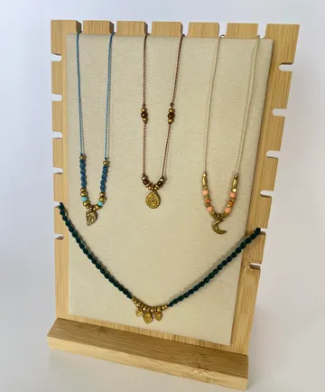 Handmade necklaces displayed on wooden stand.