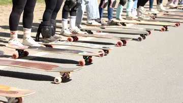 Skateboarders standing with skateboards on road.