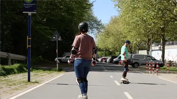 Two people skateboarding on a sunny street.