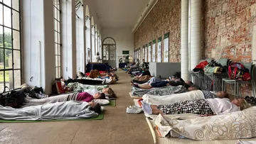 People lying on mats in a large hall.