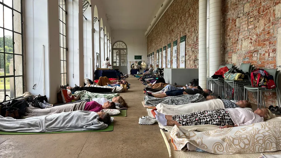 People lying on mats in a large hall.