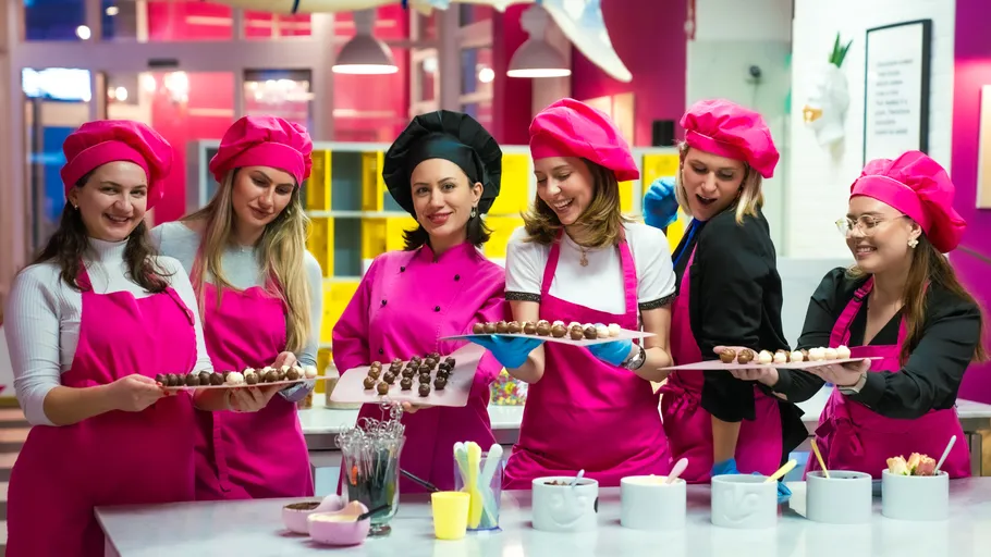 Frauen in pinken Uniformen halten Schokoladentabletts.