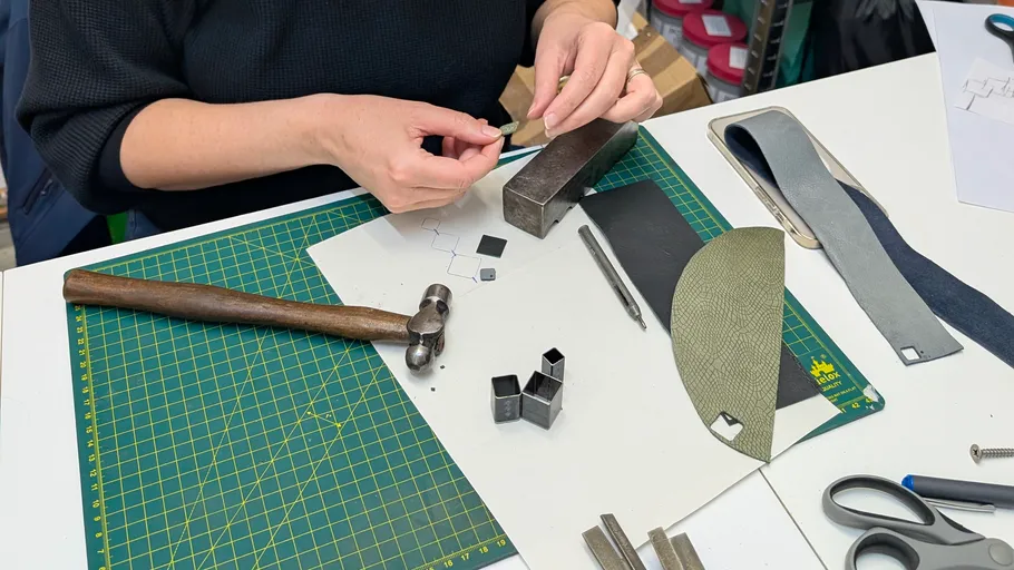 Person crafting with tools and materials on table.