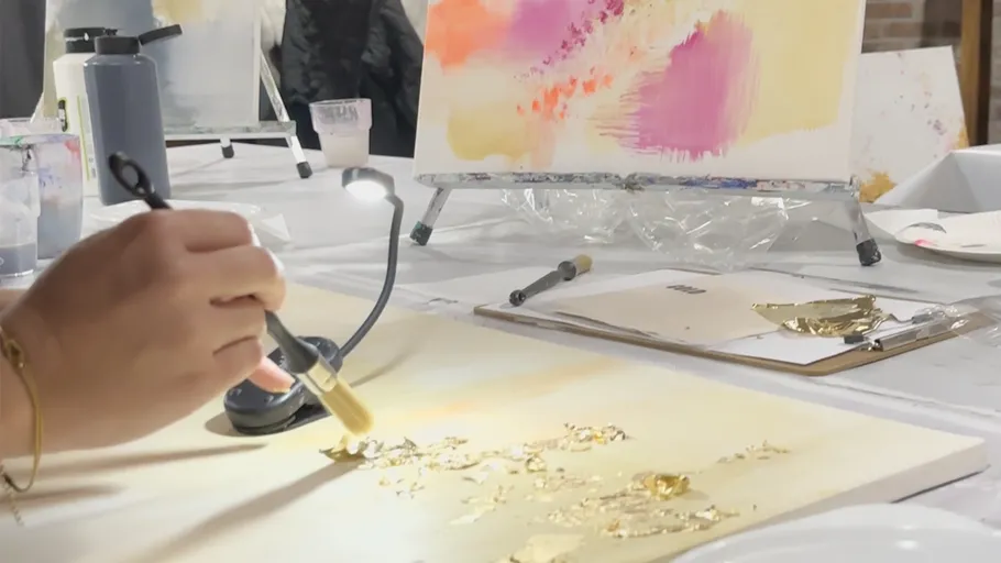 Hand trägt Blattgold auf Leinwand auf.