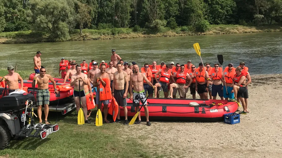 Group posing with rafts by a riverbank.