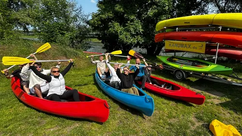 People in kayaks holding paddles, outdoor setting.