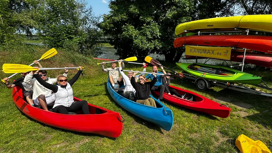 People in kayaks holding paddles, outdoor setting.