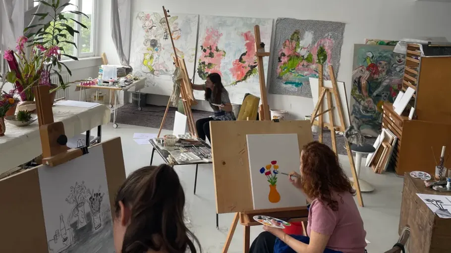 Menschen malen im Atelier mit Staffeleien.