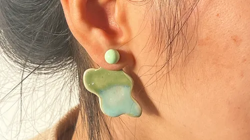Colorful earring on woman's ear, close-up view.