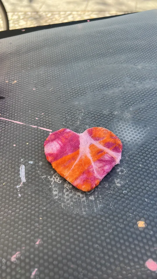 Buntes herzförmiges Blatt auf strukturierter Fläche.