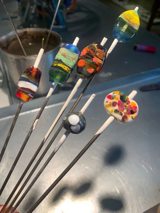 Bunte Glasperlen auf Metallstangen.