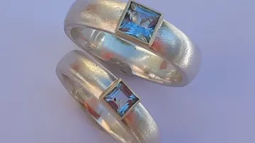 Two silver rings with blue square gems.