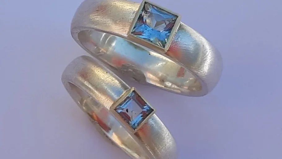 Two silver rings with blue square gems.