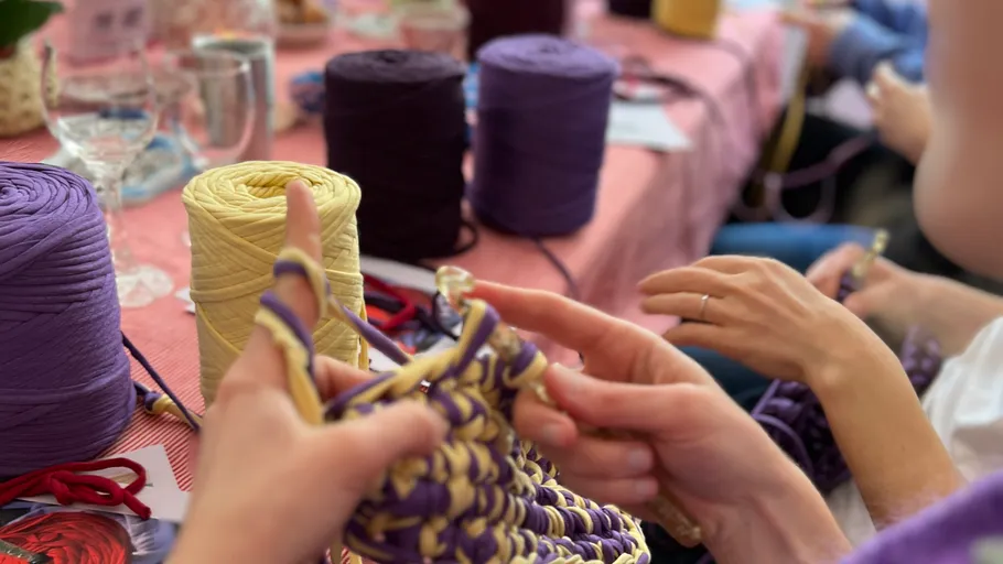 Hände stricken mit Garnen auf einem Tisch.