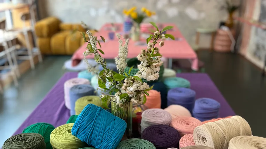 Yarn rolls and flowers on a table.