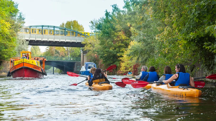 Paddler fahren auf einem Fluss unter einer Brücke.