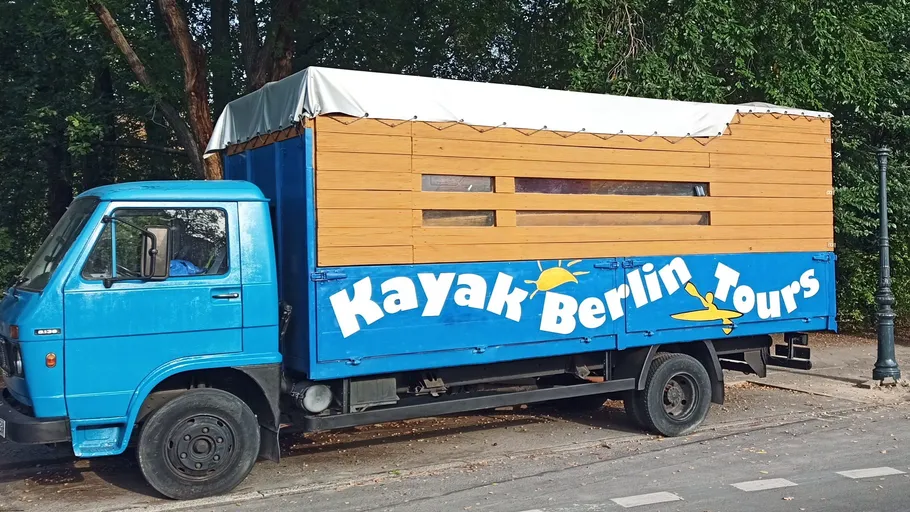 Blue truck advertising kayak tours parked roadside.
