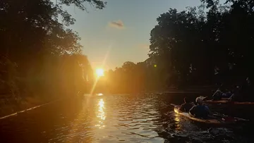Kajakfahrer paddeln bei Sonnenuntergang auf dem Fluss.