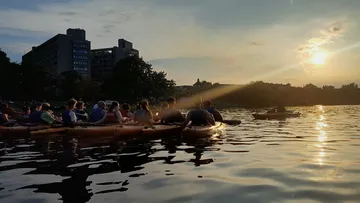 Gruppe beim Kajakfahren bei Sonnenuntergang auf Stadtsee.