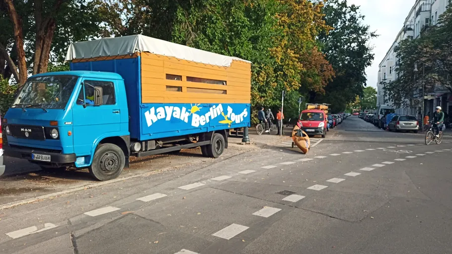 Truck parked on street, offers kayak tours.