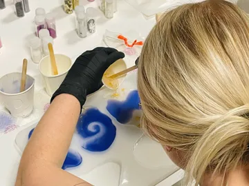 A person mixes colored resins on a table.