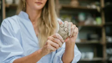 Frau formt Ton im Töpferstudio.