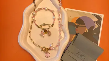 Jewelry on tray with postcard and folder.