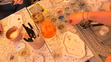 People making jewelry at a craft table.