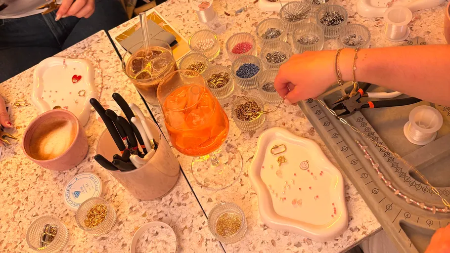 People making jewelry at a craft table.