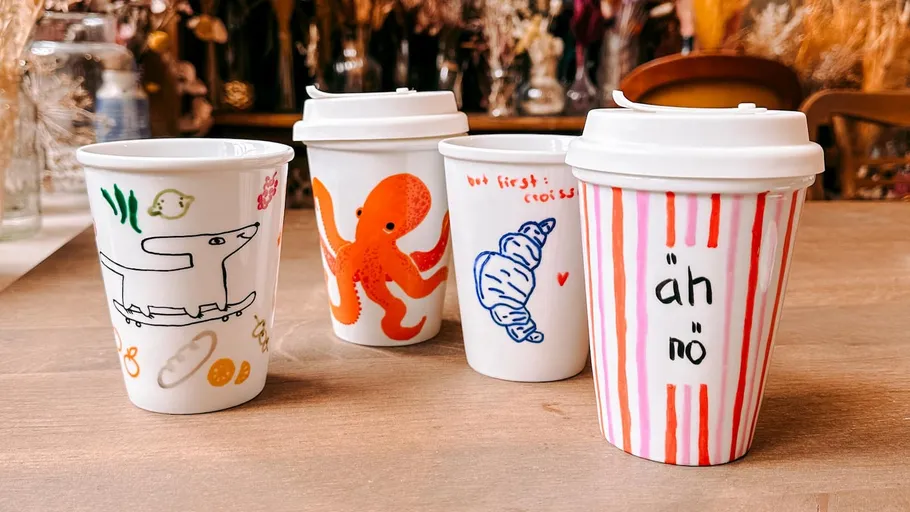 Four artistic mugs on a wooden table.