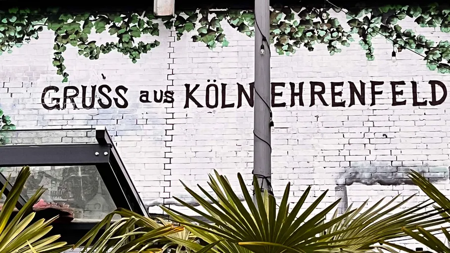 Wall with greeting sign and foliage.